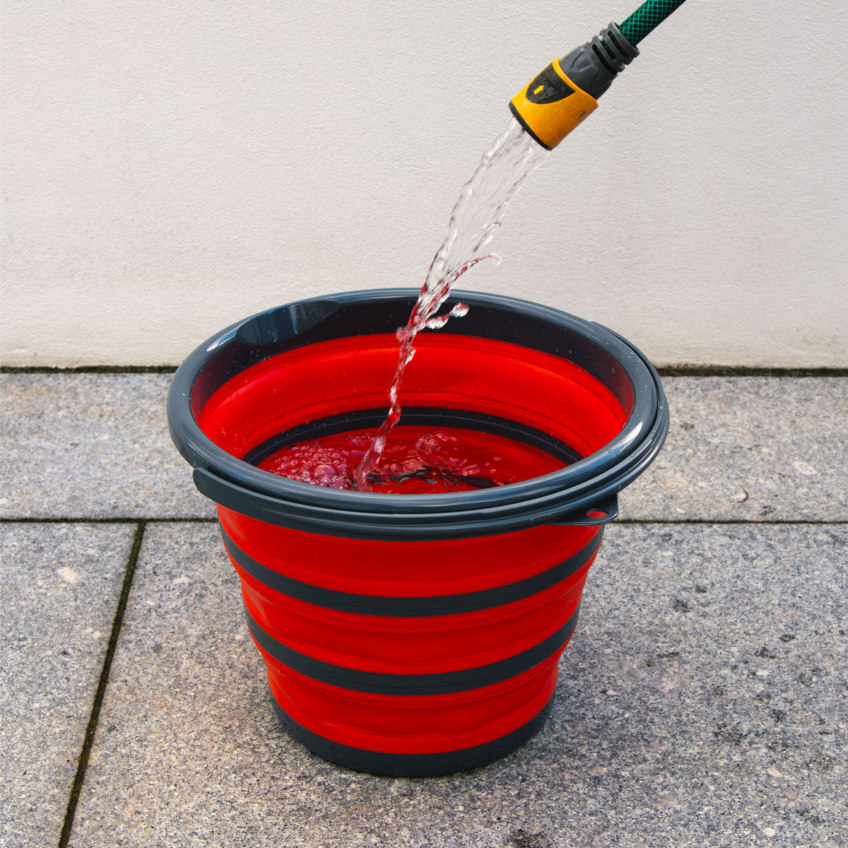 Folding bucket being filled with a garden hose