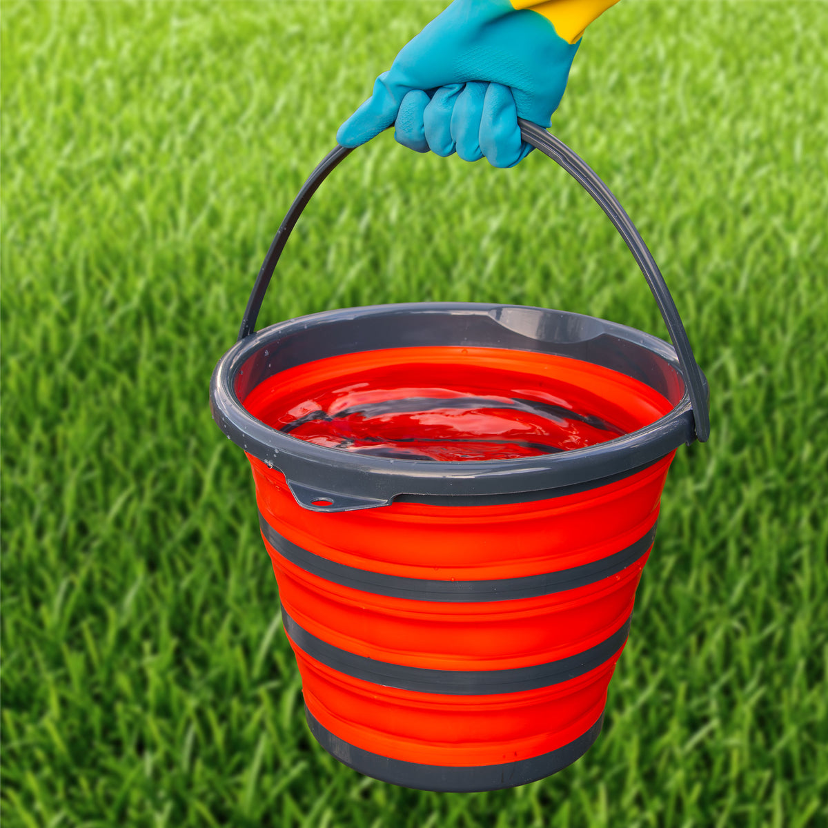 Gloved hand carrying the full 10 litre folding bucket by its handle